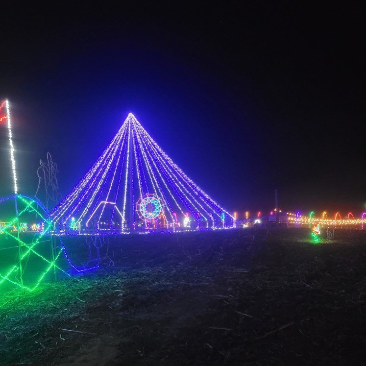 Trail+of+Light+Display+PA Colorful holiday lights illuminate a festive scene at night, featuring a large pyramid structure adorned with vibrant LED lights, alongside a decorative ferris wheel and various light displays in the background.