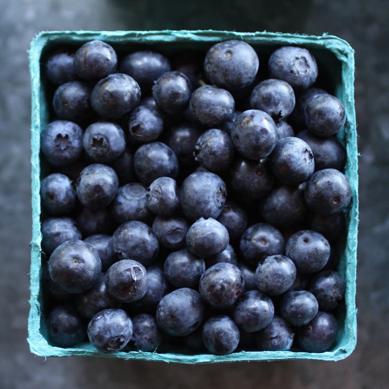 blueberries_cartons Fresh blueberries in a cardboard container, showcasing a rich blue color and plump texture, perfect for healthy snacking or baking.
