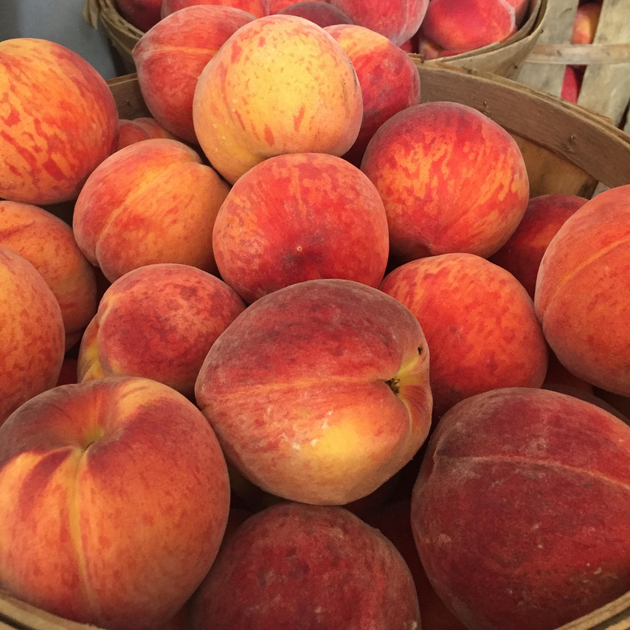 peach+photo Fresh, ripe peaches piled in wooden baskets, showcasing their vibrant orange and red hues, perfect for seasonal recipes and healthy snacks.